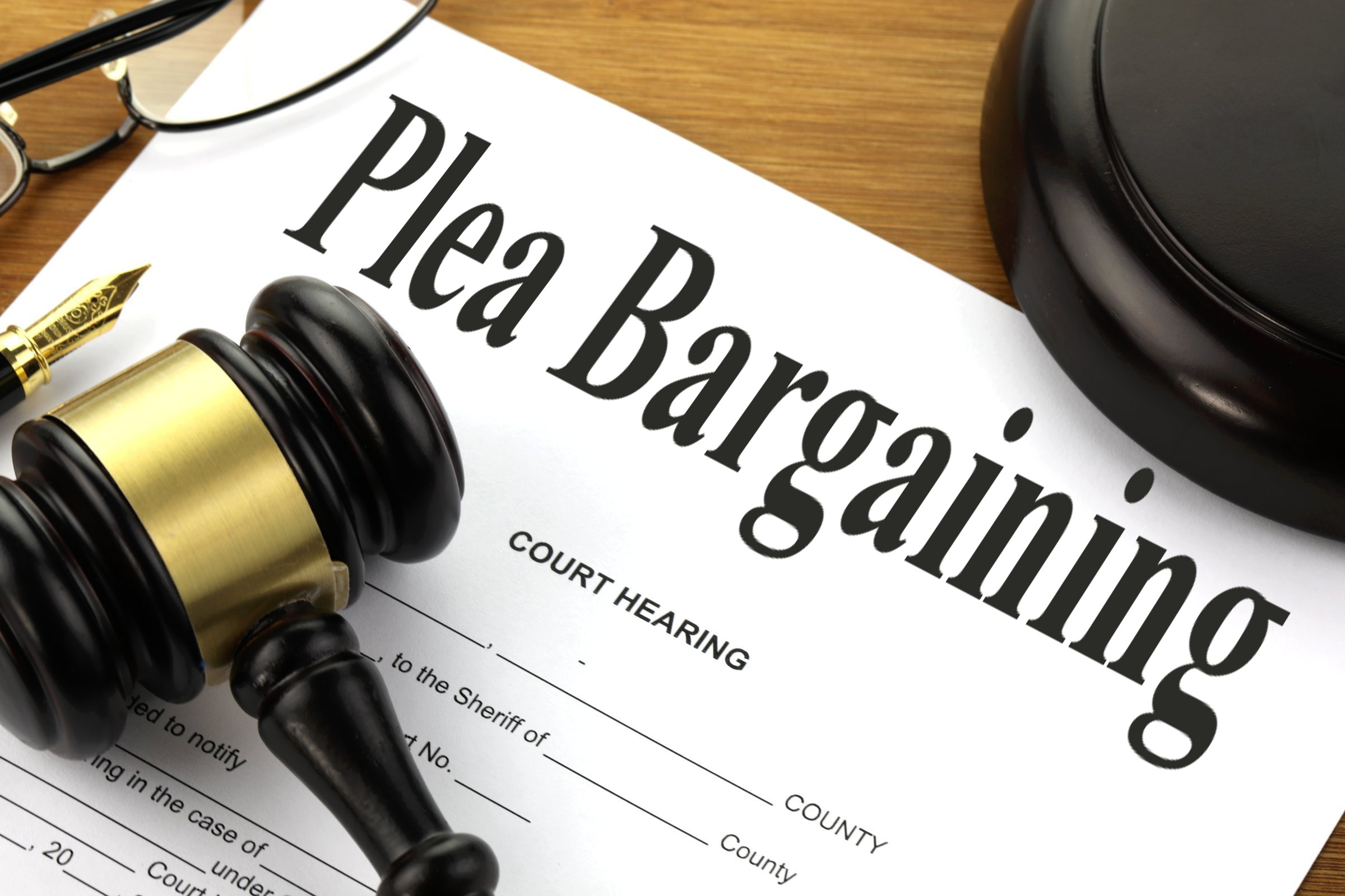 Plea bargain agreement documents with a judge gavel in a courtroom